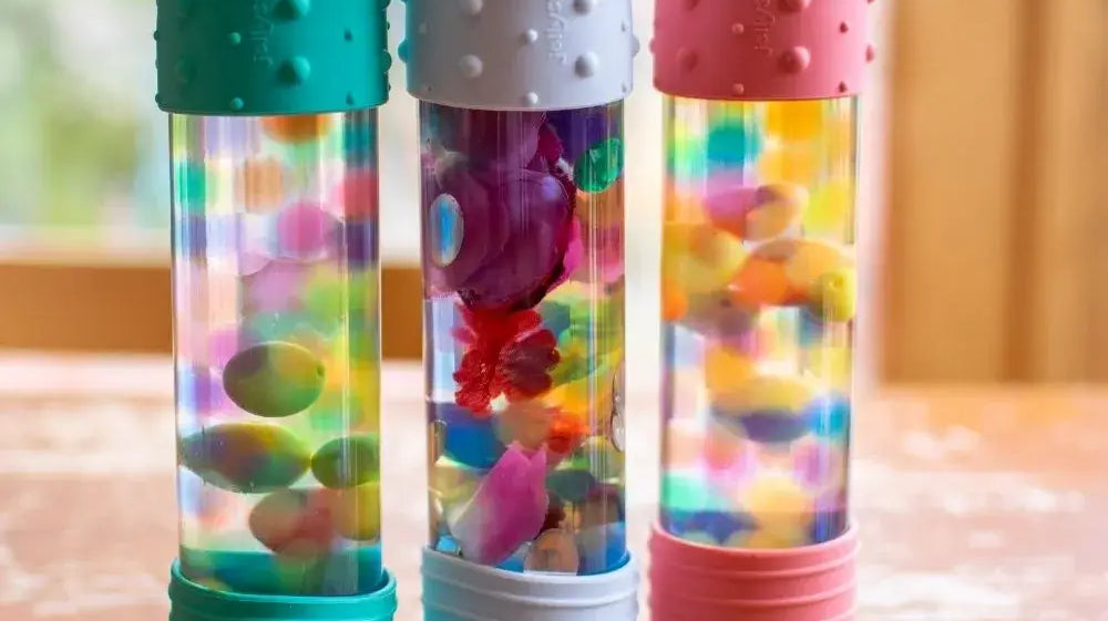 Três brinquedos sensoriais coloridos com bolhas e peças brilhantes, perfeitos para estimular os sentidos das crianças.