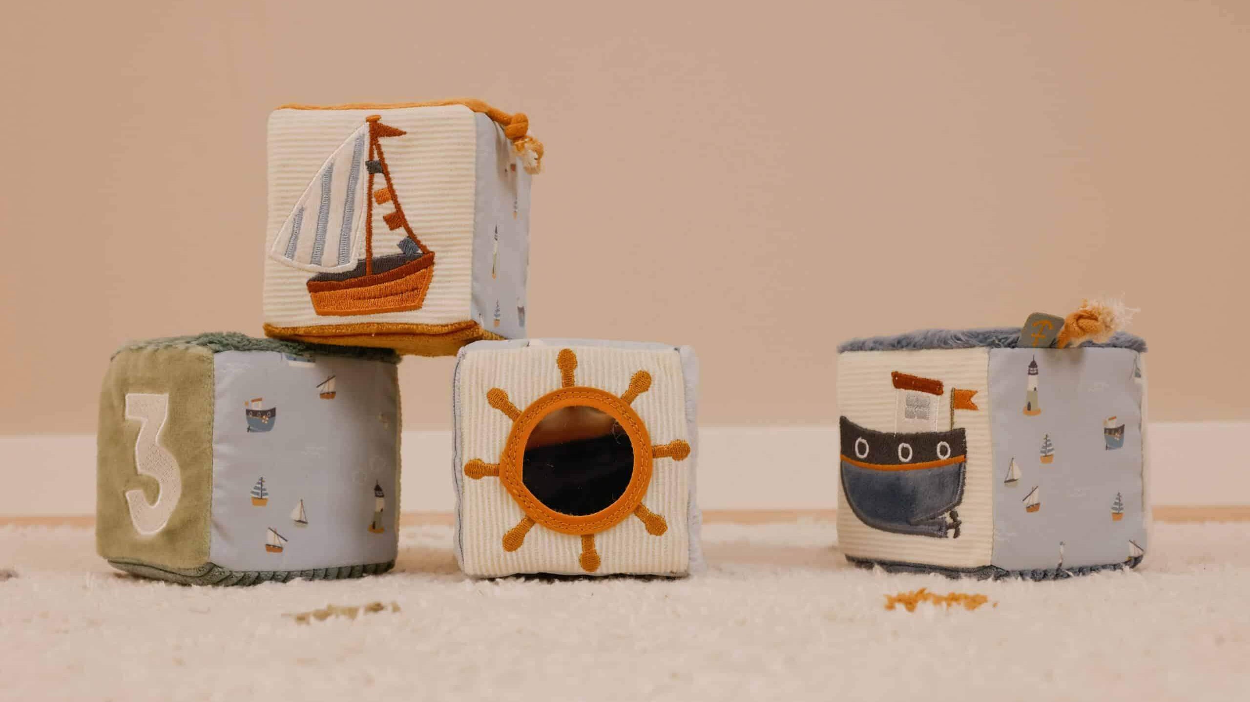 Colorful fabric blocks featuring a sailboat, sun, and ship designs for babies' playtime development.