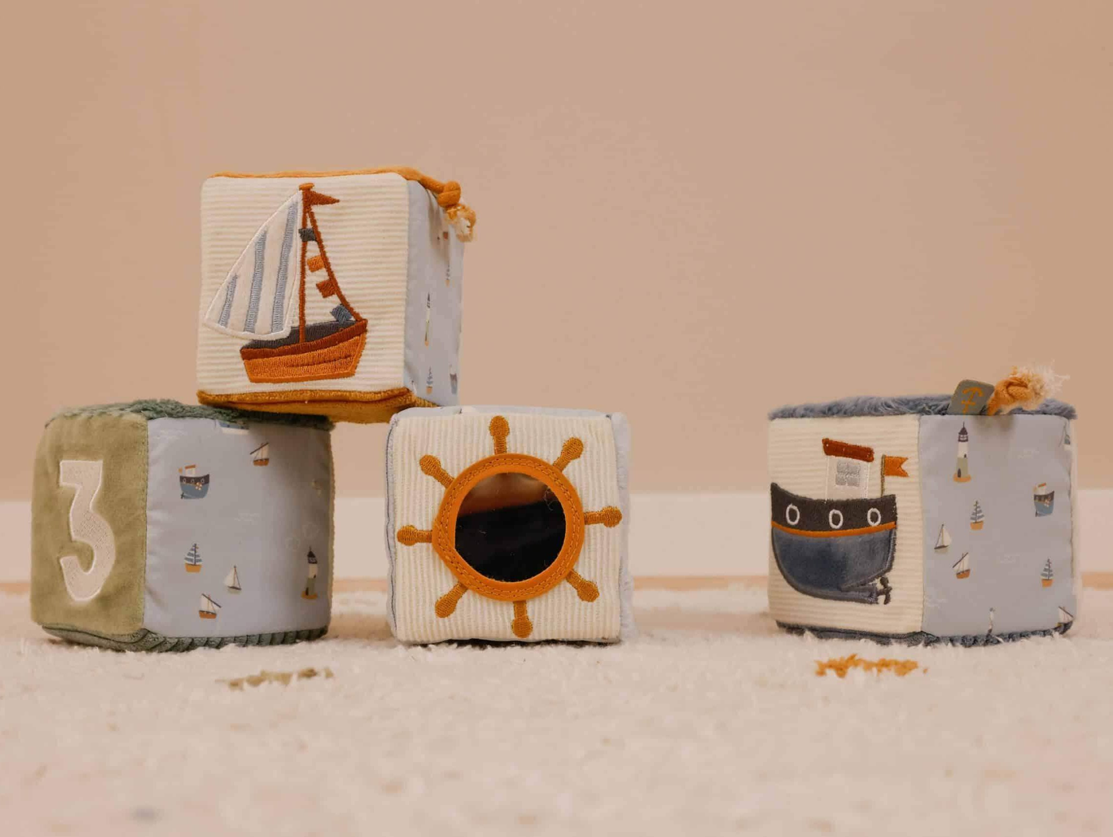 Colorful fabric blocks featuring a sailboat, sun, and ship designs for babies' playtime development.