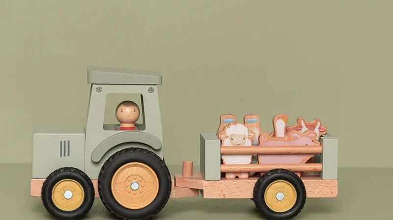 Brinquedo de madeira com trator e figuras de animais em um fundo suave verde.
