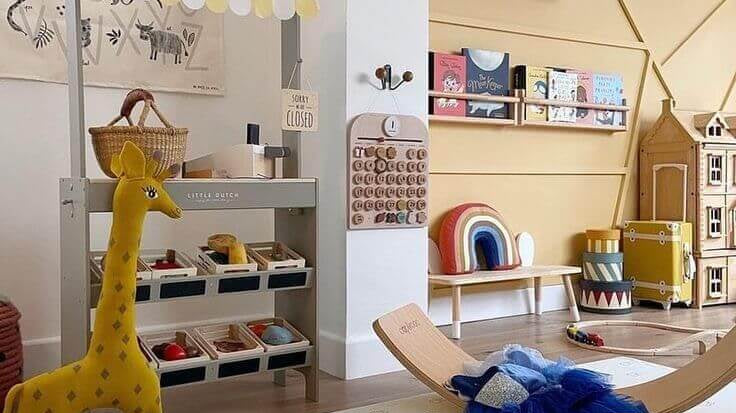 Colorido ambiente infantil com brinquedos educativos, giraffa de pelúcia e brinquedos de madeira em um espaço de brincadeiras.