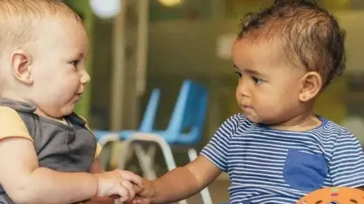 Bebés interagindo em um ambiente de creche, simbolizando a amizade e a transição para a nova fase.