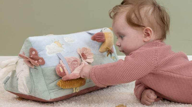 Bebé explora brinquedo educativo colorido e macio que estimula o desenvolvimento sensorial.