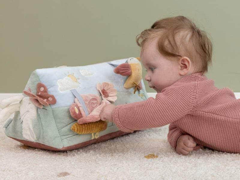 Bebé explora brinquedo educativo colorido e macio que estimula o desenvolvimento sensorial.