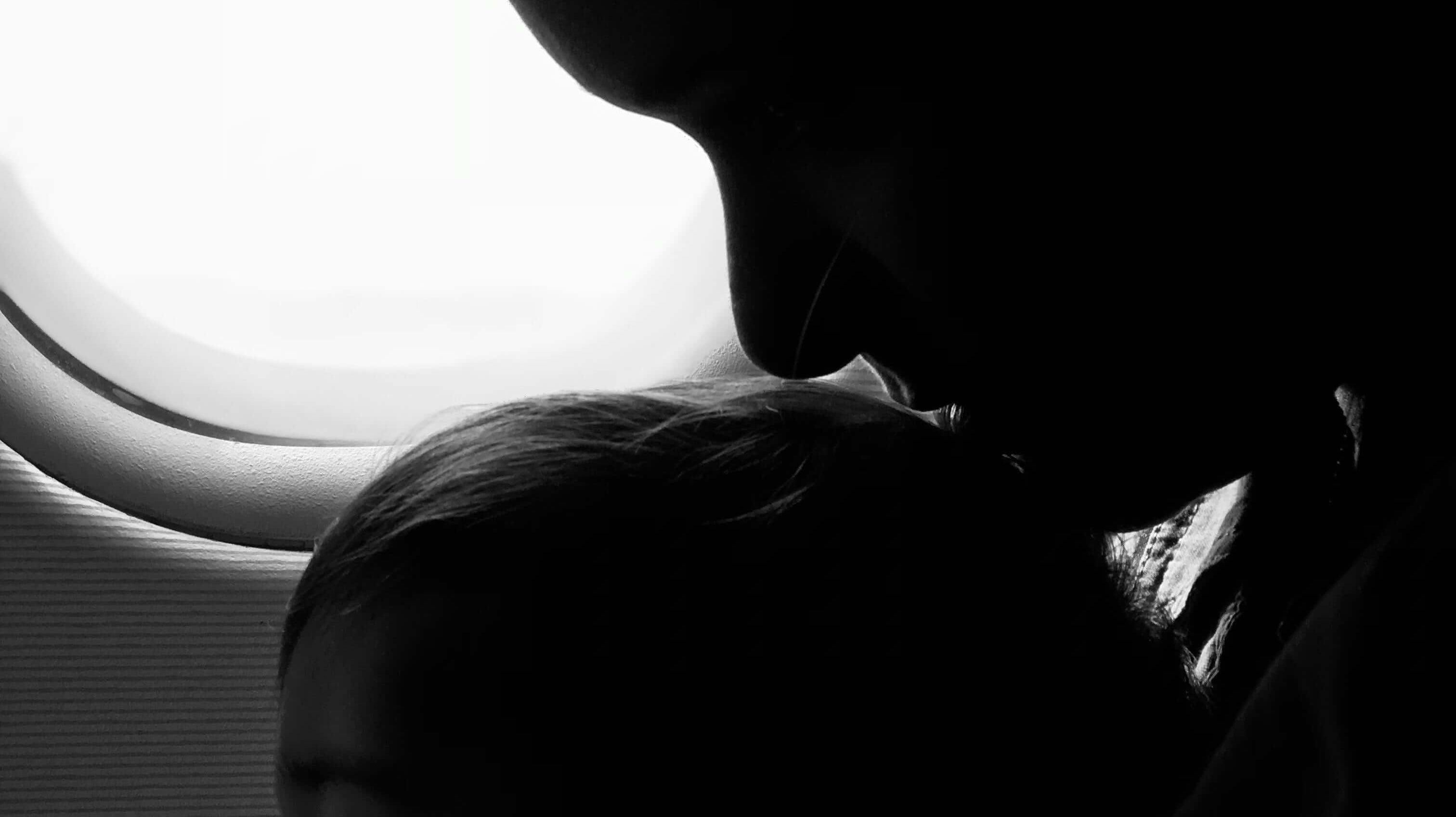 Silhueta de mãe e bebé no avião, mostrando um momento de carinho durante o voo.