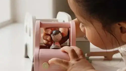 Criança brincando com um brinquedo educativo rosa e uma figura, estimulando o desenvolvimento e a criatividade.