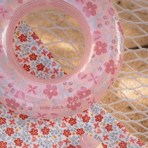 Little Dutch pink flowers inflatable pool ring on a floral fabric background, perfect for summer fun.