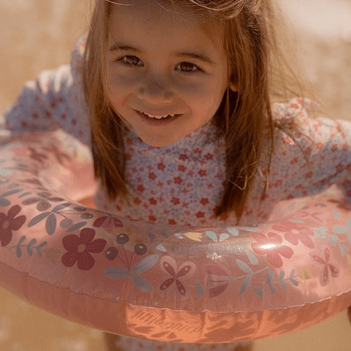 Child smiling while holding a Boia Little Dutch float with pink flower design, perfect for summer fun in the water.