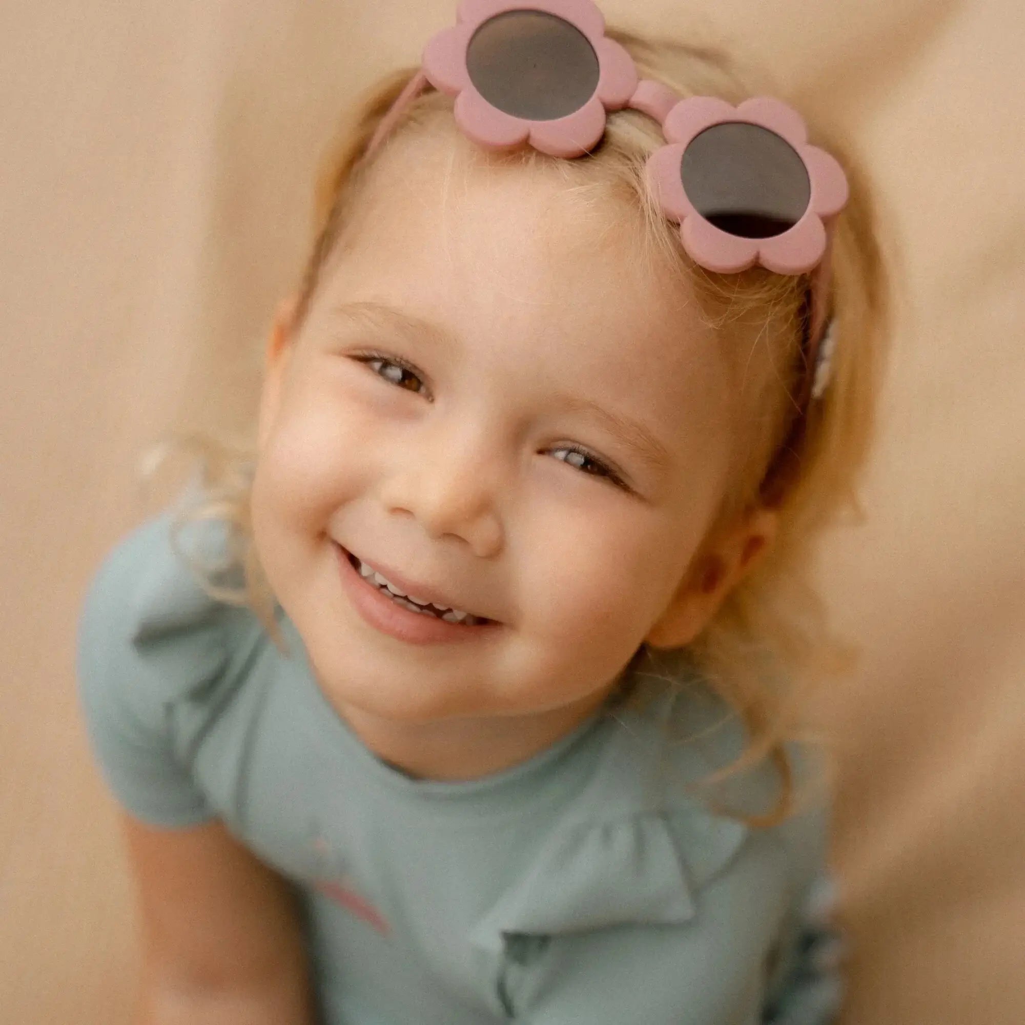Happy child wearing Flower Pink sunglasses from Little Dutch, perfect for summer sun protection.