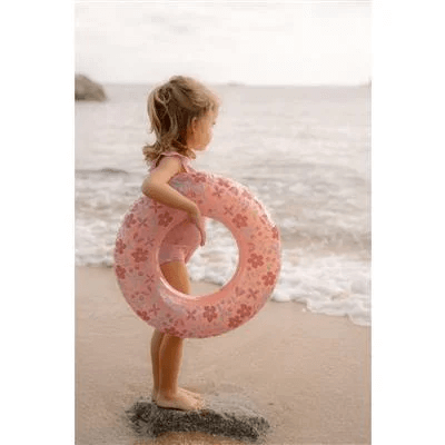 Little Dutch pink flower swim ring with a child at the beach, enjoying summer fun in the water.