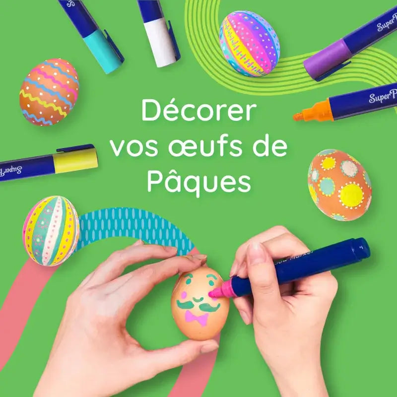 Mãos decorando ovos de Páscoa com marcadores SuperPetit em cores vibrantes sobre fundo verde.