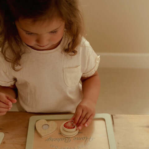 Criança usando o Conjunto de Pasteleiro Little Dutch para fazer bolachas de brincar.