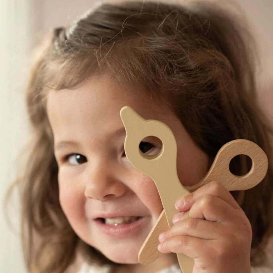 Conjunto de Cabeleireiro Little Dutch, menina segurando brinquedo de cortar cabelo em madeira.