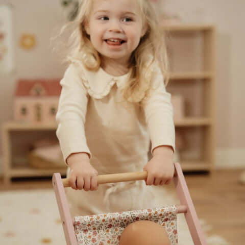 Carrinho de Bonecas em Madeira Rosa - Little Dutch com uma menina brincando na sala.