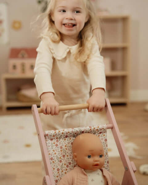 Carrinho de Bonecas em Madeira Rosa - Little Dutch com uma menina brincando na sala.