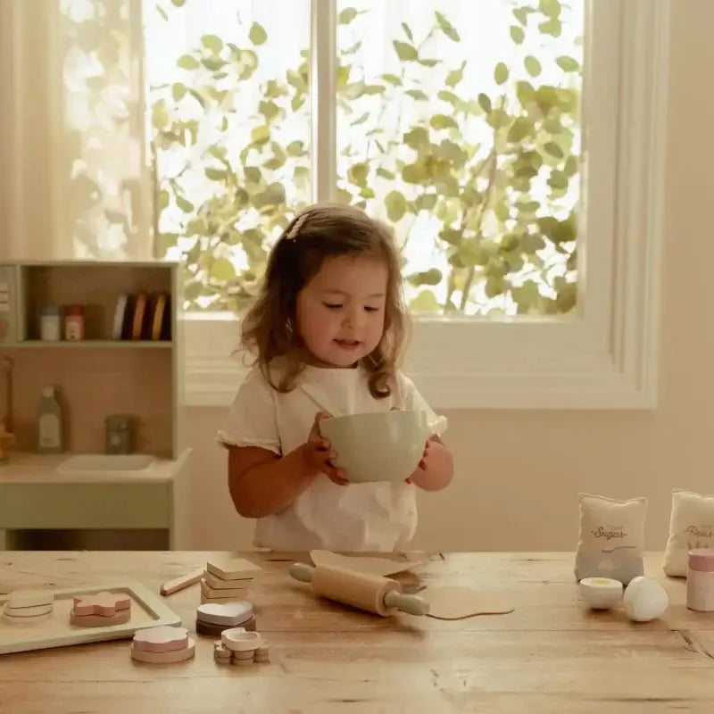Conjunto de Pasteleiro Little Dutch: criança segurando uma tigela em cozinha de brinquedo com ingredientes.