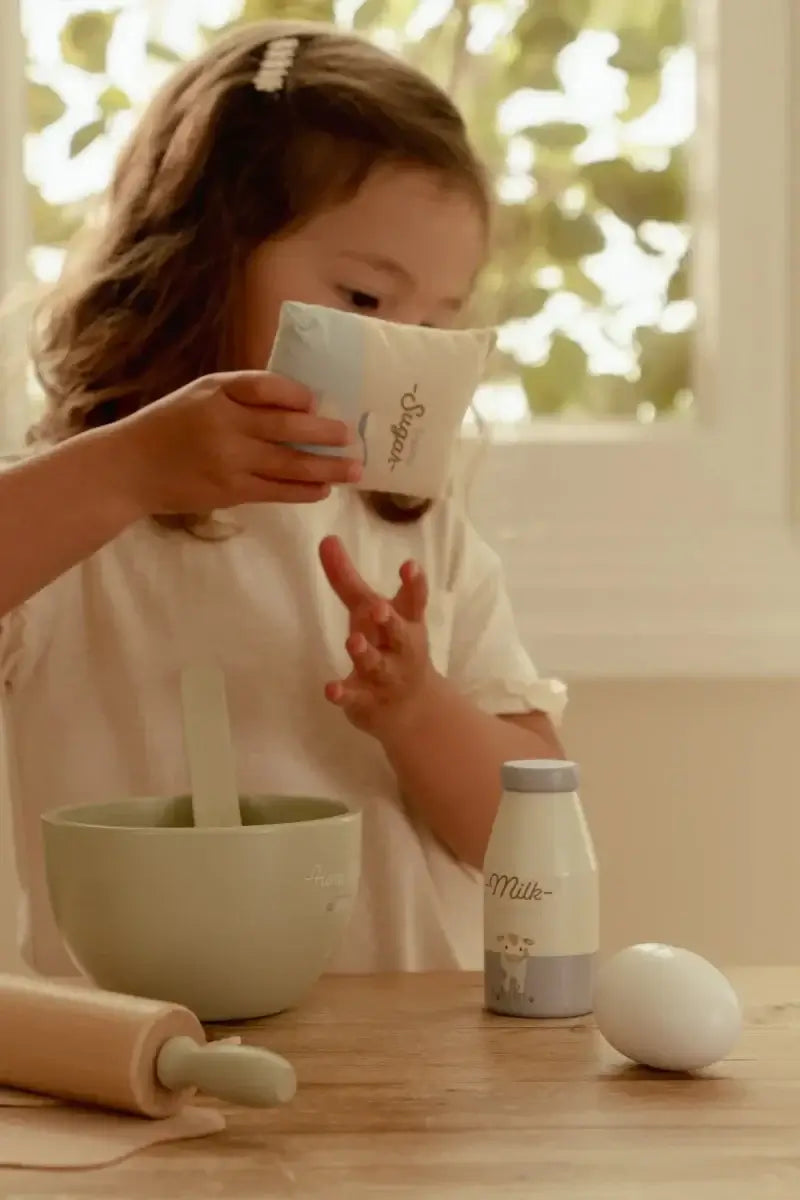 Menina usando o Conjunto de Pasteleiro Little Dutch com taça e ingredientes para bolachas.