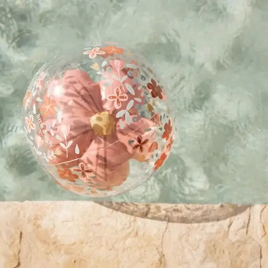 Bola insuflável de praia 3D com flores pink, flutuando na água de uma piscina cristalina.