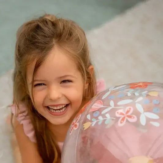 Little Dutch 3D inflatable beach ball with pink flowers, enjoyed by a happy child in a playful setting.