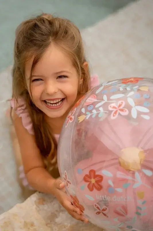 Little Dutch 3D inflatable beach ball with pink flowers, enjoyed by a happy child in a playful setting.