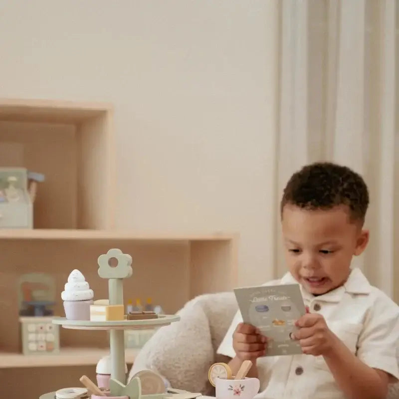 Criança brincando com a Bandeja de Bolos Little Dutch, organizando chá com doces e menu ilustrado.