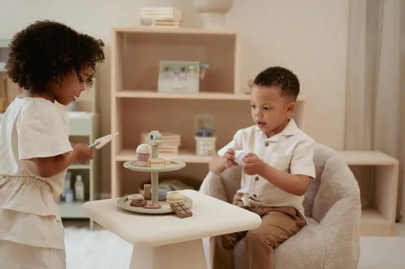 Crianças brincando com a Bandeja de Bolos Little Dutch e doces durante a hora do chá.