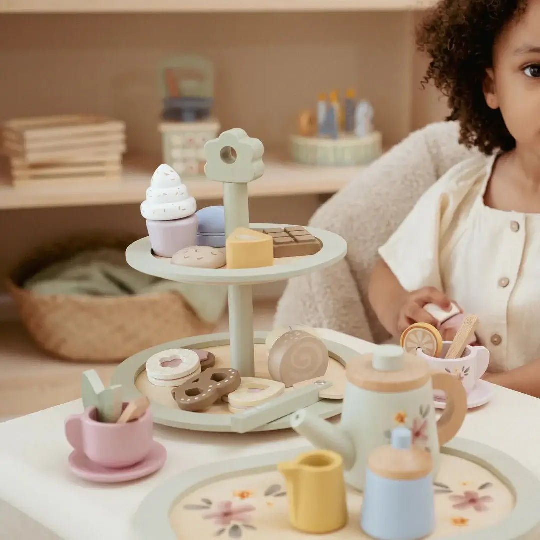 Bandeja de Bolos Little Dutch com andares decorada com doces e acompanhada por criança em ambiente de chá.