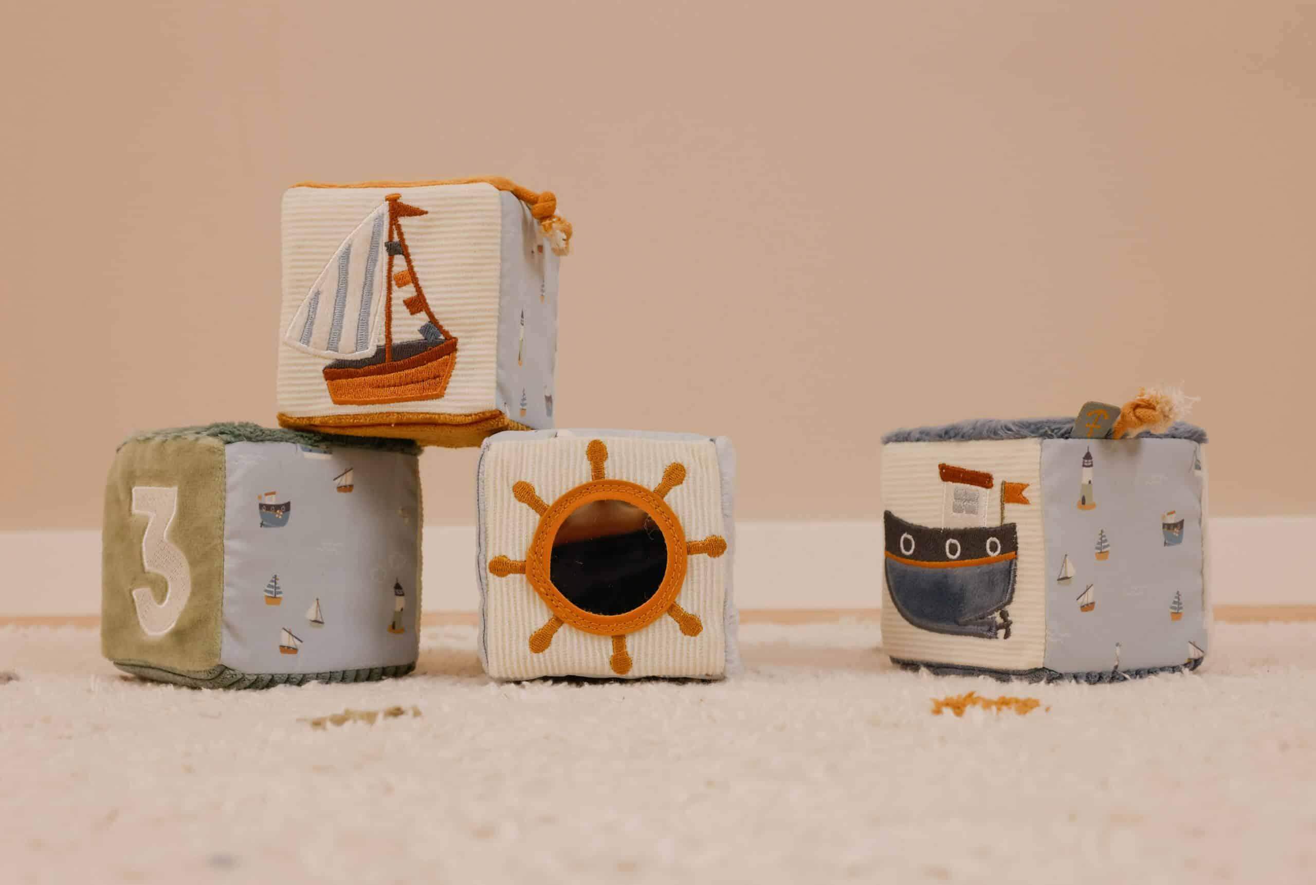 Colorful fabric blocks featuring a sailboat, sun, and ship designs for babies' playtime development.