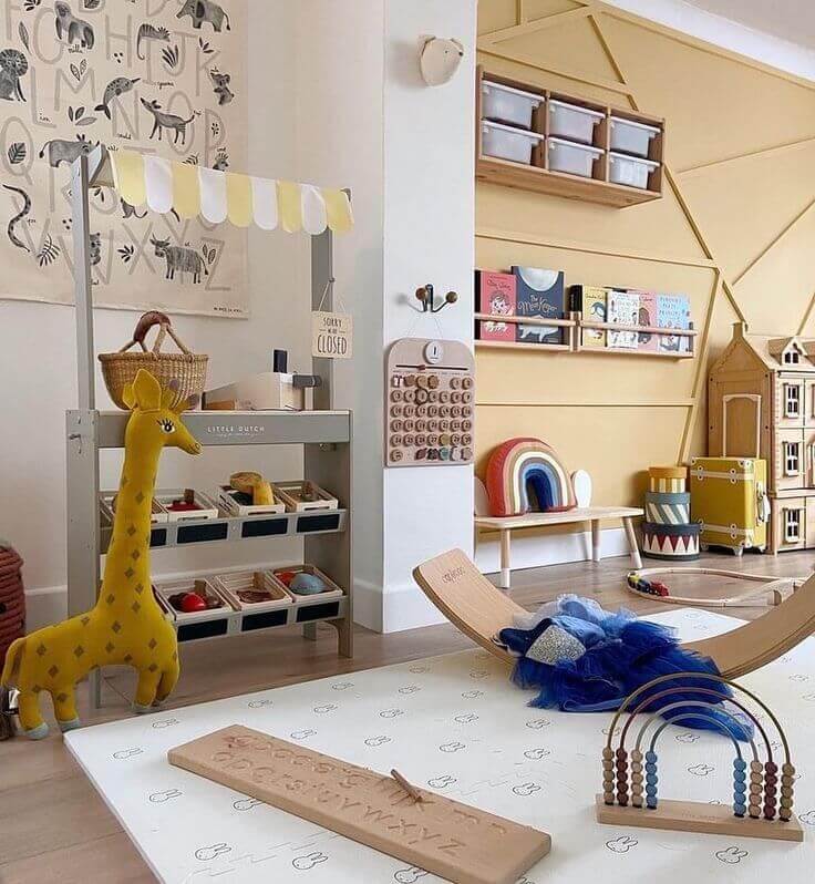 Colorido ambiente infantil com brinquedos educativos, giraffa de pelúcia e brinquedos de madeira em um espaço de brincadeiras.