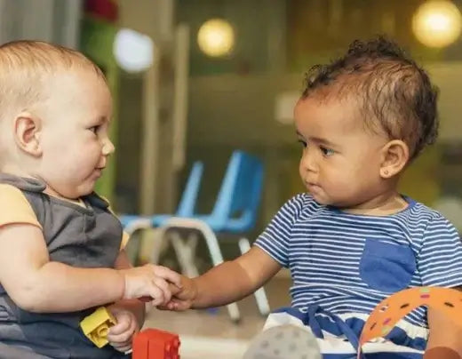 Bebés interagindo em um ambiente de creche, simbolizando a amizade e a transição para a nova fase.
