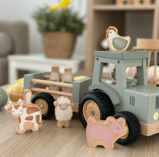 Colorful wooden farm toys including a tractor, animals, and milk bottles on a playful surface.