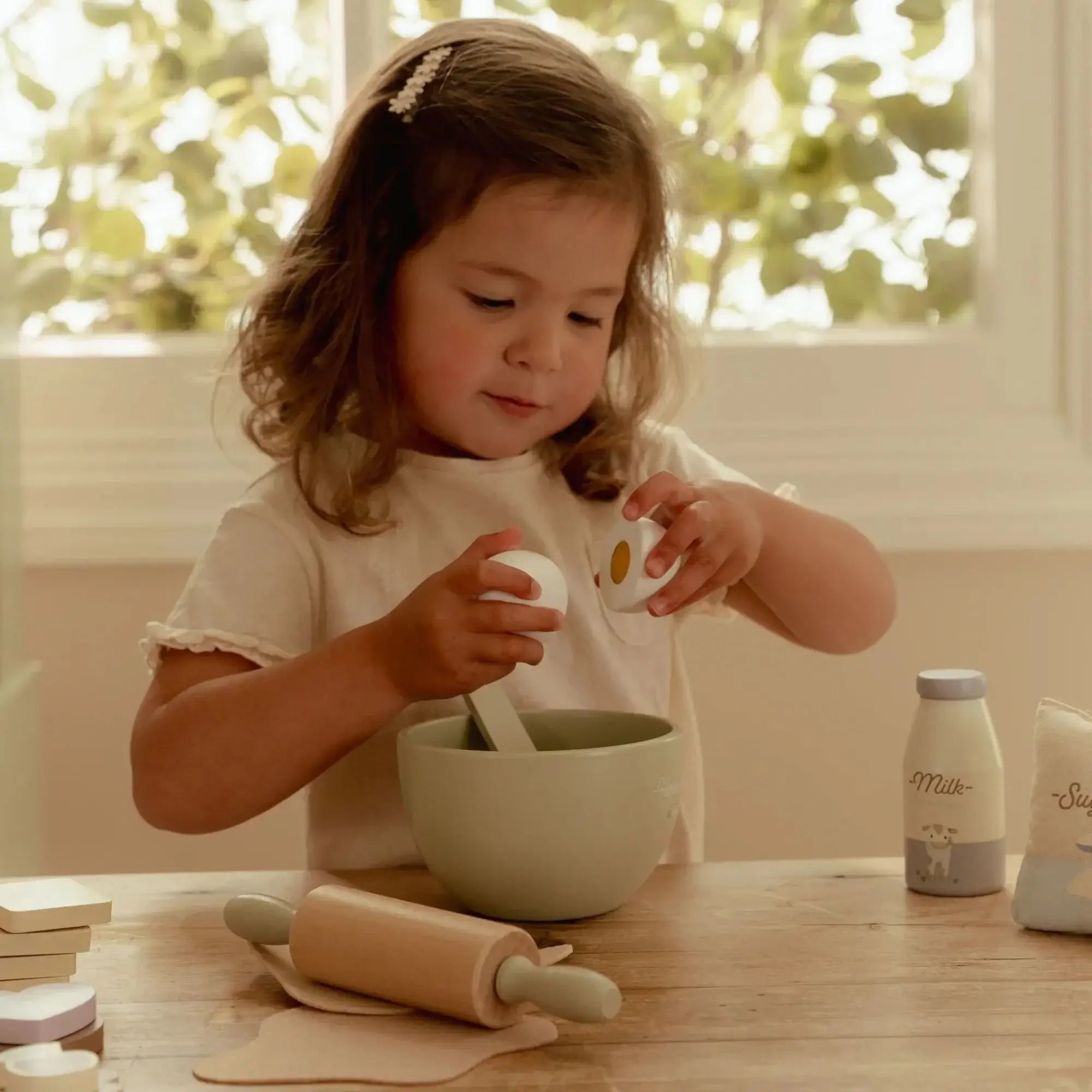 Criança usando o Conjunto de Pasteleiro Little Dutch, preparando bolachas de brincar com uma taça de mistura.