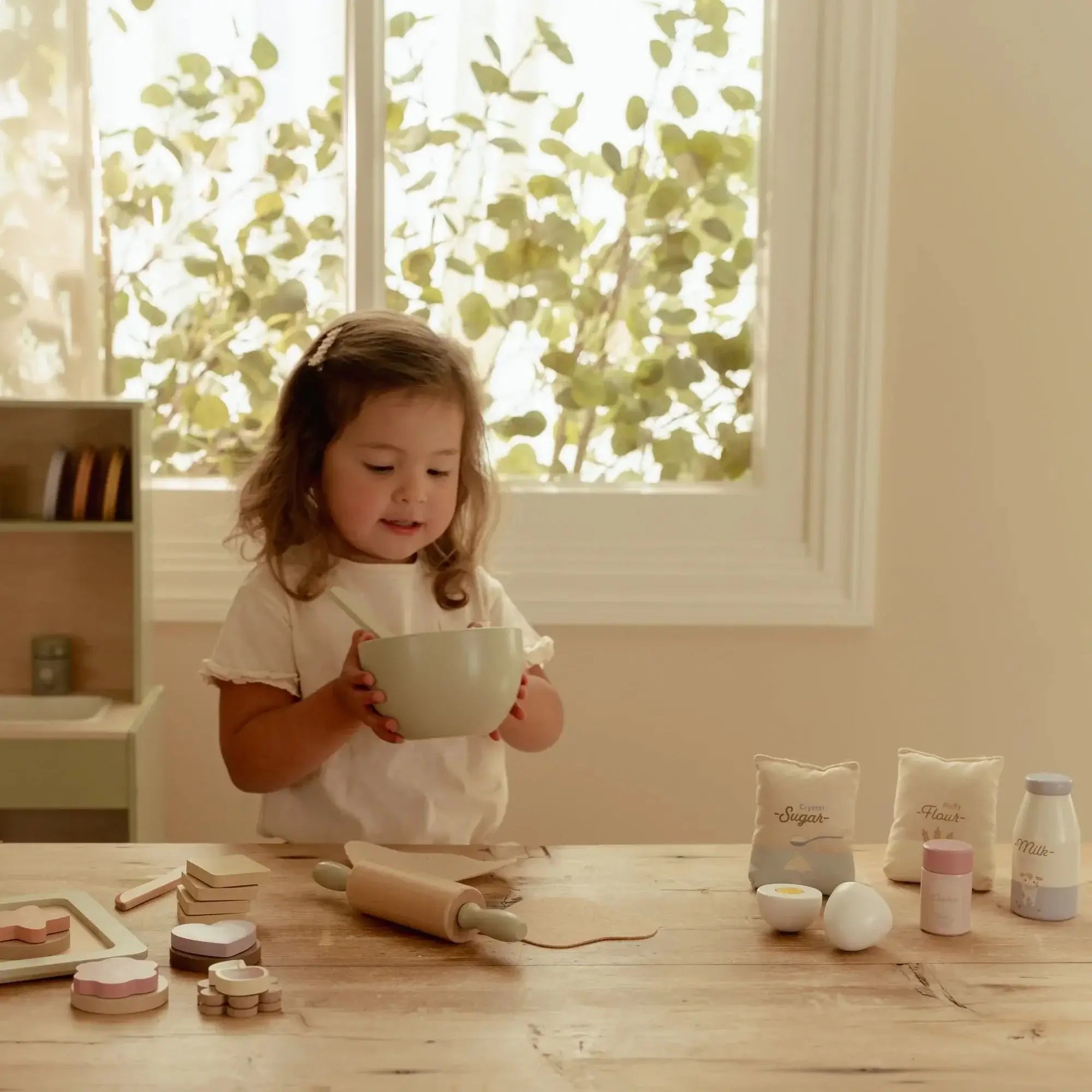 Conjunto de Pasteleiro Little Dutch: criança segurando uma tigela em cozinha de brincar.