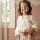 Menina sorridente usando o Conjunto de Cabeleireiro Little Dutch com acessórios de beleza.