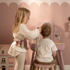 Criança brincando com o Conjunto de Cabeleireiro Little Dutch em um espelho, com acessórios de beleza.