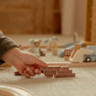 Pista com Grua de Construção - Little Dutch com criança segurando peças de construção de madeira.