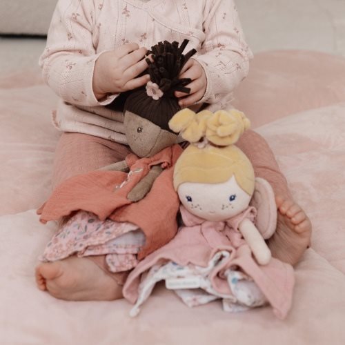 Bebe brincando com bonecas Doudou Fada Evi da Little Dutch, envolvidas em roupas coloridas e suaves.