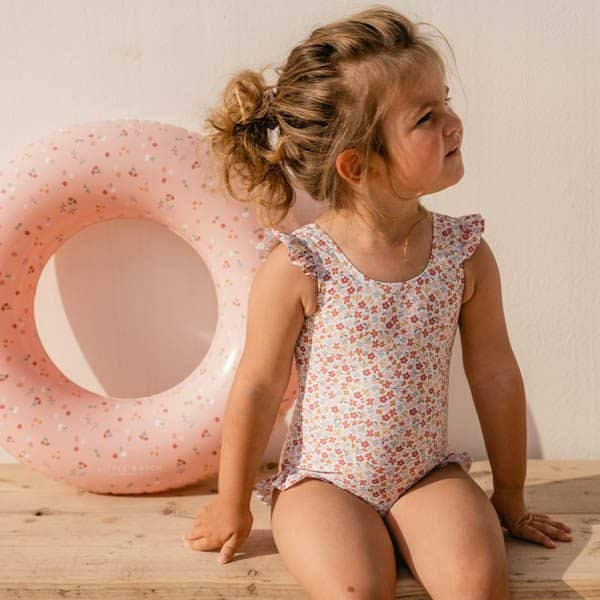 "Criança usando Fato de Banho Folhos - Summer Flowers da Little Dutch, 3-6 meses, com boia rosa ao fundo"