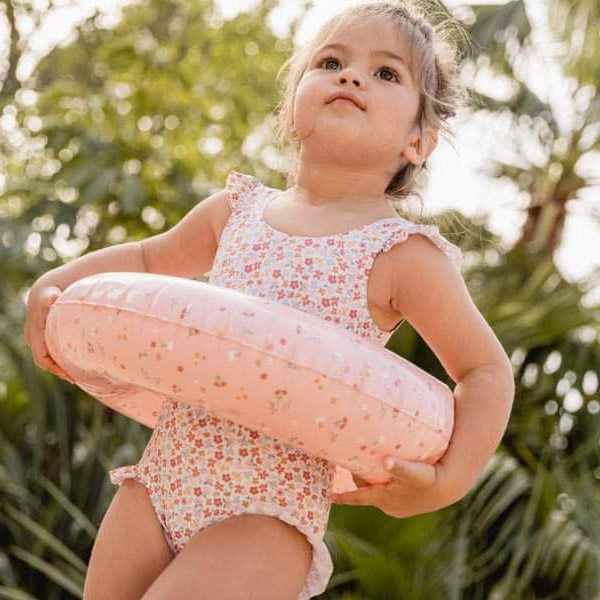 Little girl wearing Fato de Banho Folhos - Summer Flowers swimsuit holding a pink float.