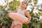 Little girl wearing Fato de Banho Folhos - Summer Flowers swimsuit holding a pink float.