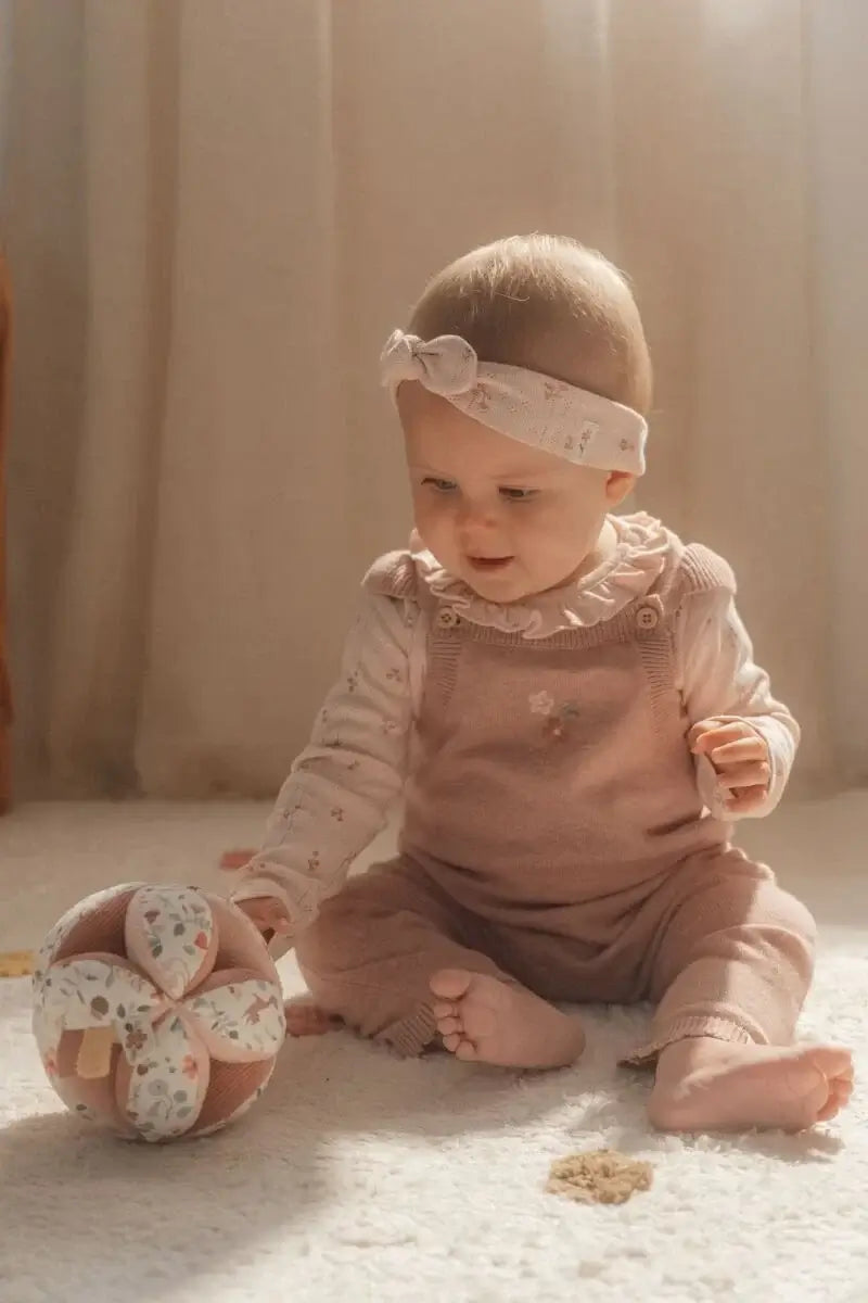 bebê feliz brincando com bola sensorial de atividades Fairy Garden da Little Dutch em um ambiente iluminado.