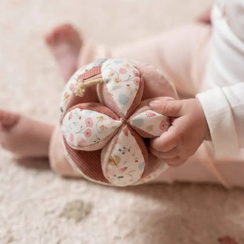 Baby holding Little Dutch Fairy Garden sensory activity ball, featuring soft textures and pastel floral design.