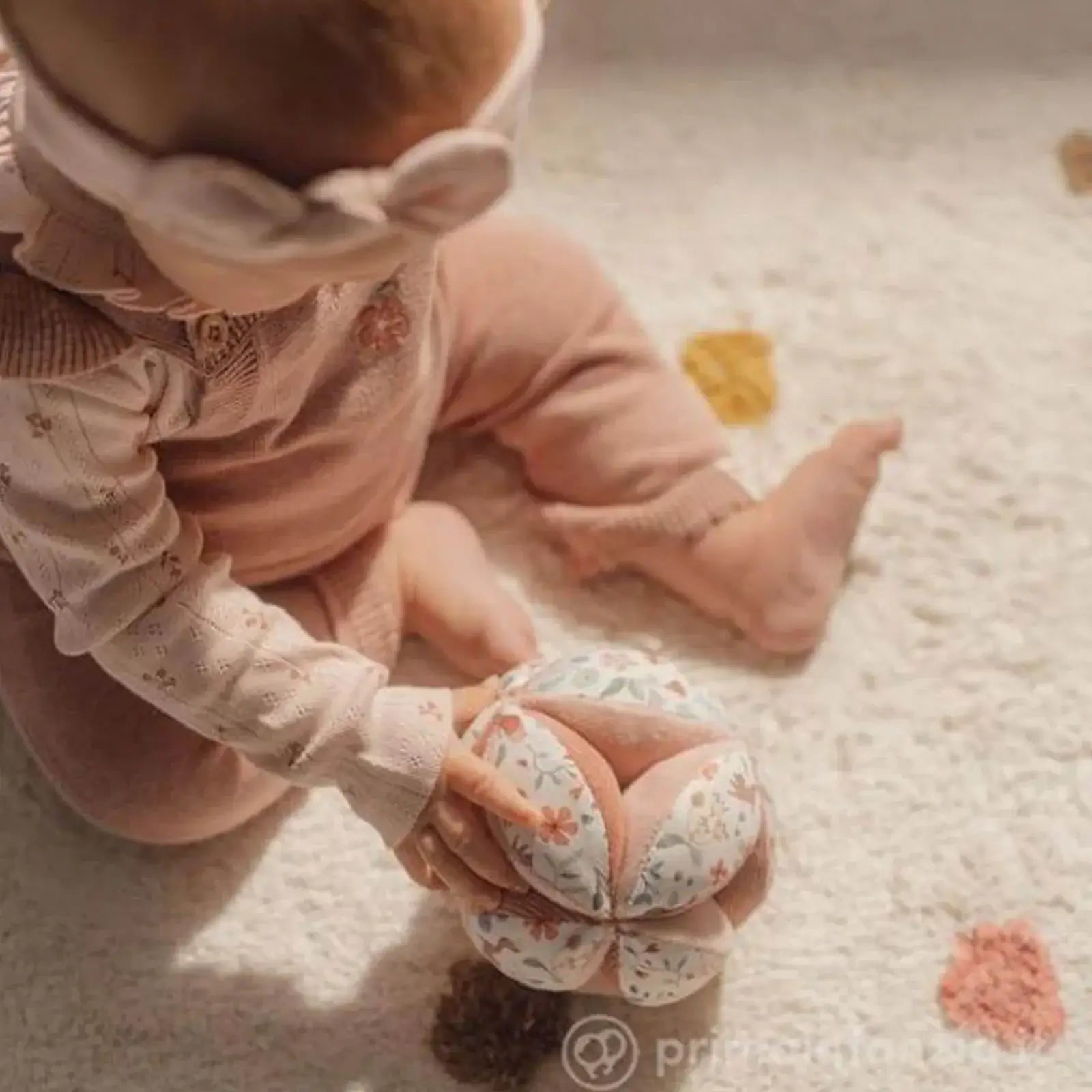 Bebé brincando com a Bola Sensorial de Atividades Fairy Garden da Little Dutch em um tapete macio.