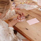 Child creating art with stickers in the Little Dutch Fairy Garden creativity kit on a wooden table.