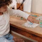 Child engaged in creative play with crafting materials from the Little Dutch Forest Friends kit at a wooden table.