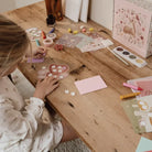 Child crafting with the Little Dutch XL Fairy Garden kit, surrounded by colorful supplies on a wooden table.