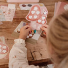 Criança segurando uma ficha de artesanato em forma de cogumelo com decoração, parte do Kit de Criatividade XL Fairy Garden.