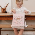 Girl excitedly opening the XL Fairy Garden creativity kit from Little Dutch at a wooden table.