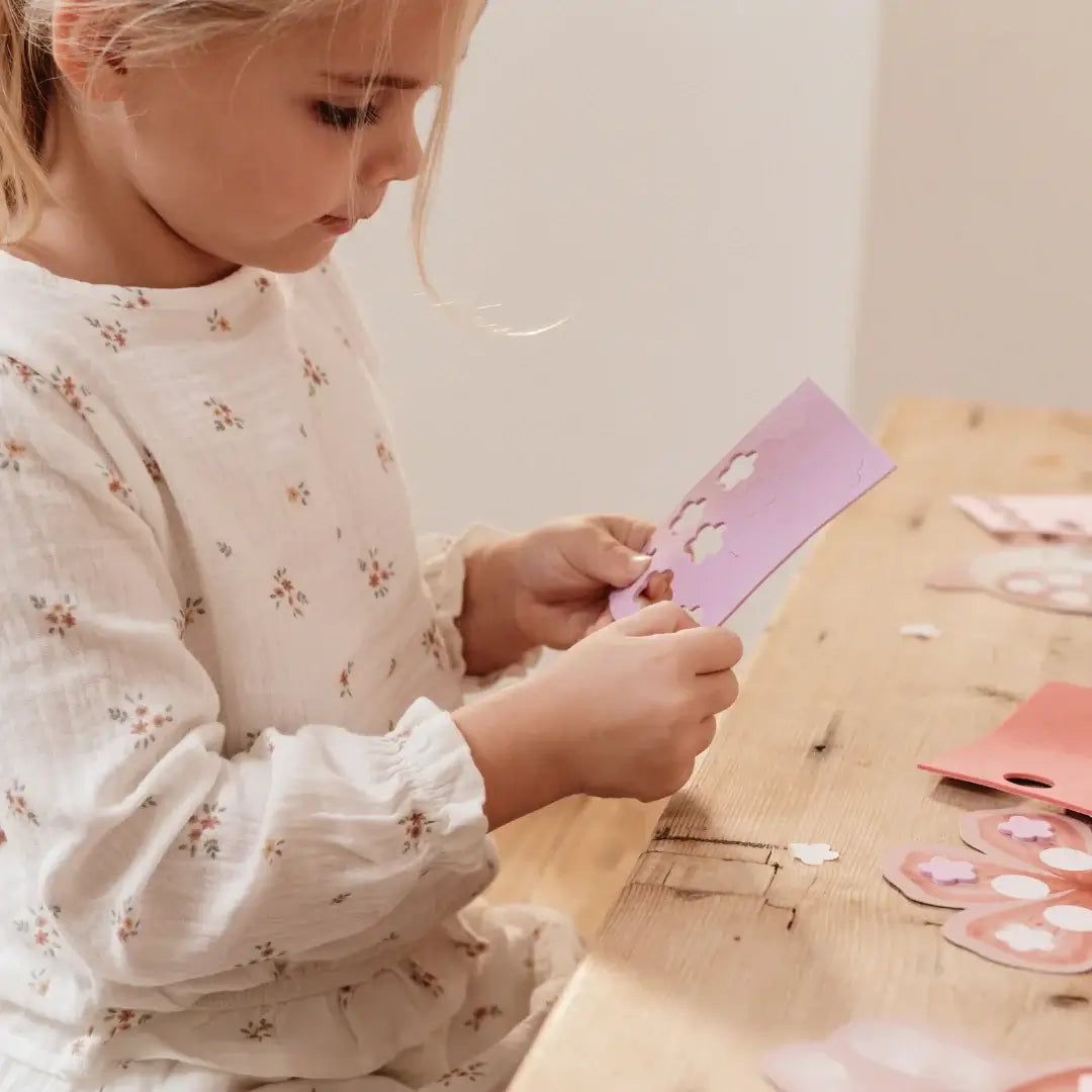 Young girl crafting with colorful paper in a creative workspace, engaged in imaginative play.