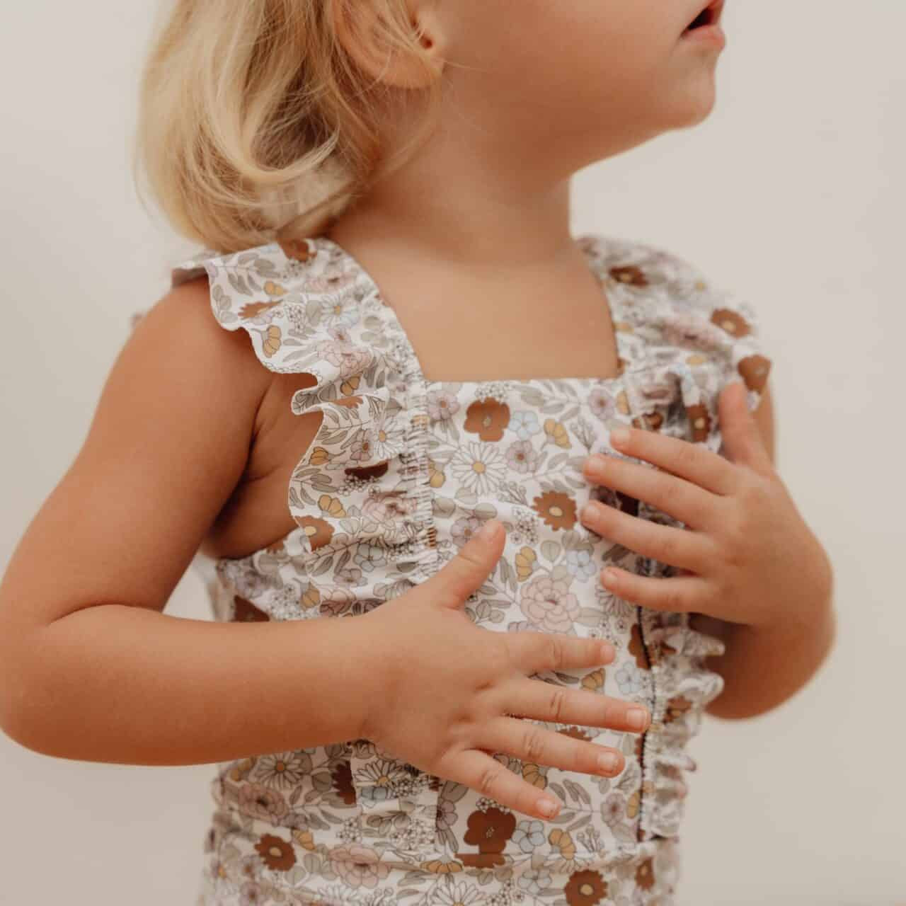 Toddler wearing a vintage floral ruffled swimsuit from Little Dutch.